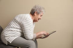 Elderly Woman With Poor Posture Using Tablet On Beige Background Royalty Free Stock Photography