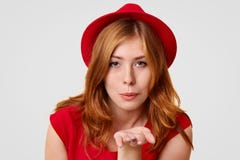 Elegancka młoda kobieta robi lotniczemu buziakowi, wyraża jej miłości mąż, ubierający w modnym czerwonym kapeluszu i t koszula, g obrazy royalty free Elegancka młoda kobieta robi lotniczemu buziakowi, wyraża jej miłości mąż, ubierający w modnym czerwonym kapeluszu i t koszula, g obrazy royalty free