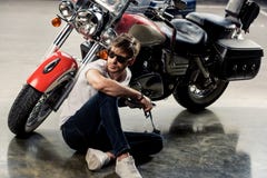 Elegancki młody człowiek siedzi blisko motocyklu i patrzeje daleko od w okularach przeciwsłonecznych zdjęcie stock Elegancki młody człowiek siedzi blisko motocyklu i patrzeje daleko od w okularach przeciwsłonecznych zdjęcie stock
