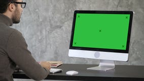 Elegant businessman analyzing data in office on his computer. Back view to the monitor. Green Screen Mock-up Display. stock video footage Elegant businessman analyzing data in office on his computer. Back view to the monitor. Green Screen Mock-up Display. stock video footage