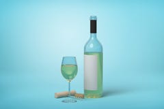 White wine glass beside bottle and cork. Elegant composition of a white wine glass next to a bottle with cork, on a subtle blue background