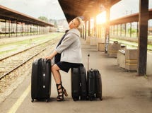 Elegant woman sitting on suitcases and waiting for the train royalty free stock images Elegant woman sitting on suitcases and waiting for the train royalty free stock images
