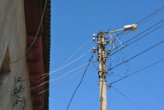 Elektro ceramische zekeringen en zwarte draden onder leidak op muur en oude lantaarn, mening van grond aan hoogste, blauwe hemel stock fotografie Elektro ceramische zekeringen en zwarte draden onder leidak op muur en oude lantaarn, mening van grond aan hoogste, blauwe hemel stock fotografie