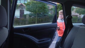 Elementary-school student goes to school. The boy out of the car and waving to his parents
