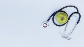An elevated view of stethoscope around the green apple stock photo An elevated view of stethoscope around the green apple stock photo