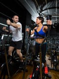 Elliptical walker trainer man and woman at black gym stock images Elliptical walker trainer man and woman at black gym stock images