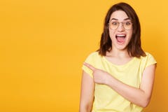 Emotional cheerful young female poses isolated over yellow background in studio, opening her mouth widely with shock, shows royalty free stock images Emotional cheerful young female poses isolated over yellow background in studio, opening her mouth widely with shock, shows royalty free stock images