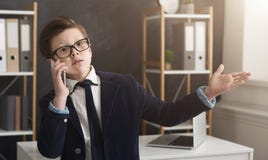 Emotioneel weinig jongen in kostuum die ernstige bedrijfsbespreking hebben stock foto Emotioneel weinig jongen in kostuum die ernstige bedrijfsbespreking hebben stock foto