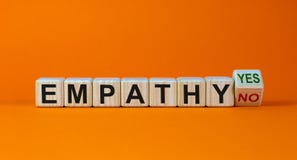 Empathy yes or no symbol. Concept words `empathy yes` and `empathy no` on wooden cubes on a beautiful orange background.