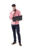 Empleado joven del hombre de negocios que se sostiene y que trabaja en el ordenador portátil fotos de archivo libres de regalías Empleado joven del hombre de negocios que se sostiene y que trabaja en el ordenador portátil fotos de archivo libres de regalías