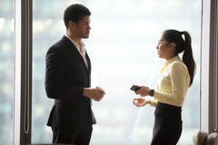 Empleados milenarios que tienen charla casual cerca de ventanas de la oficina imagen de archivo Empleados milenarios que tienen charla casual cerca de ventanas de la oficina imagen de archivo