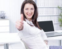 Employee shows a thumbs up, sitting at the Desk stock photo Employee shows a thumbs up, sitting at the Desk stock photo