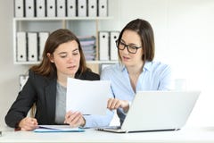 Employés de bureau coworking comparant des documents photo stock Employés de bureau coworking comparant des documents photo stock