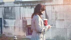 Empresaria atractiva al aire libre con el teléfono móvil y el café almacen de metraje de vídeo Empresaria atractiva al aire libre con el teléfono móvil y el café almacen de metraje de vídeo