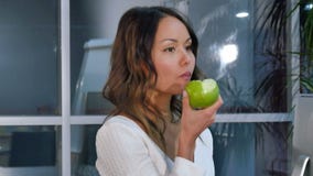 Empresaria bonita que come la manzana verde en la oficina metrajes Empresaria bonita que come la manzana verde en la oficina metrajes