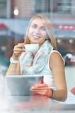 Empresaria joven que mira la pantalla de la almohadilla táctil mientras que se coloca en café imagen de archivo libre de regalías Empresaria joven que mira la pantalla de la almohadilla táctil mientras que se coloca en café imagen de archivo libre de regalías