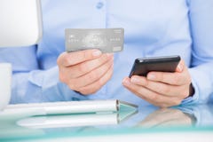 Empresaria que sostiene el teléfono móvil y la tarjeta de crédito fotografía de archivo Empresaria que sostiene el teléfono móvil y la tarjeta de crédito fotografía de archivo
