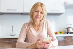 Empresaria seria de la Edad Media que usa un smartphone imagen de archivo libre de regalías Empresaria seria de la Edad Media que usa un smartphone imagen de archivo libre de regalías