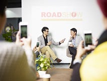Empresário asiático novo que está sendo entrevistado durante o roadshow fotografia de stock royalty free Empresário asiático novo que está sendo entrevistado durante o roadshow fotografia de stock royalty free