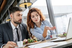 Empresários que têm o almoço de negócio no restaurante que senta-se comendo o café bebendo da salada que olha o portátil imagens de stock Empresários que têm o almoço de negócio no restaurante que senta-se comendo o café bebendo da salada que olha o portátil imagens de stock