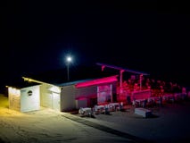 Empty beach bar with bar and chairs and tables lit with pink and white lights at night stock illustration Empty beach bar with bar and chairs and tables lit with pink and white lights at night stock illustration