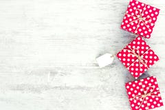 Empty card tied over red dotted gift box. Red dotted gift boxes over white wood background. Copy space. royalty free stock images Empty card tied over red dotted gift box. Red dotted gift boxes over white wood background. Copy space. royalty free stock images