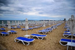 Empty empty beach with folded beach umbrellas, blue beach chair stock photography Empty empty beach with folded beach umbrellas, blue beach chair stock photography