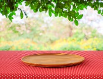 Empty round wooden tray on red polka dot tablecloth over blur tr Royalty Free Stock Photos Empty round wooden tray on red polka dot tablecloth over blur tr Royalty Free Stock Photos