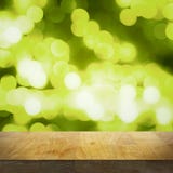 Empty wooden top table and bright blurred green background with lights and bokeh, focus on tabletop royalty free stock photography Empty wooden top table and bright blurred green background with lights and bokeh, focus on tabletop royalty free stock photography