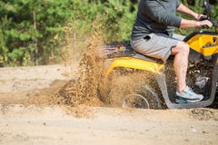 En ATV-quadbike får fastnad i en sandig väg nära skog och hahjul-snurrandet som gör en sprej av sand royaltyfria bilder En ATV-quadbike får fastnad i en sandig väg nära skog och hahjul-snurrandet som gör en sprej av sand royaltyfria bilder