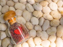 En dekorativ förälskelseglasflaska med färgrik sand inom på vit stenbakgrund arkivfoton En dekorativ förälskelseglasflaska med färgrik sand inom på vit stenbakgrund arkivfoton