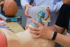 En deltagare i utbildninghåll en syremaskering med två händer med en sjuksköterska som ventilventilating via ambubag royaltyfri bild En deltagare i utbildninghåll en syremaskering med två händer med en sjuksköterska som ventilventilating via ambubag royaltyfri bild