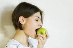 En flicka med ett kort hÃ¥r äter ett grönt äpple arkivbilder En flicka med ett kort hÃ¥r äter ett grönt äpple arkivbilder