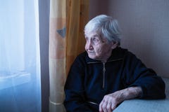 En gammal kvinna ser longingly ut fönstret av hennes hus fotografering för bildbyråer En gammal kvinna ser longingly ut fönstret av hennes hus fotografering för bildbyråer