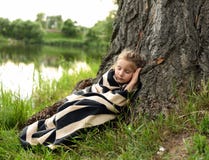 En gullig liten flicka som sover under ett enormt träd under den frodiga gröna naturen arkivbild En gullig liten flicka som sover under ett enormt träd under den frodiga gröna naturen arkivbild