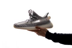 En hand rymmer en Adidas Yeezy 350 V2 statisk i dess hand Släppt på December 26, 2018 royaltyfria foton En hand rymmer en Adidas Yeezy 350 V2 statisk i dess hand Släppt på December 26, 2018 royaltyfria foton