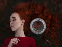 En härlig flicka med långa röda hårsömnar bredvid en guldfisk i ett akvarium Ung redheaded kvinna Lein på en höst arkivbild En härlig flicka med långa röda hårsömnar bredvid en guldfisk i ett akvarium Ung redheaded kvinna Lein på en höst arkivbild