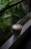 En kopp av cappuccino p? en f?nsterbr?da royaltyfri bild En kopp av cappuccino p? en f?nsterbr?da royaltyfri bild