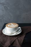 En kopp av cappuccino på en brun servett arkivbilder En kopp av cappuccino på en brun servett arkivbilder