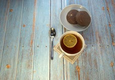 En kopp te med citronen, en sked och två chokladkakor på en plattalögn på en trätabell royaltyfri foto En kopp te med citronen, en sked och två chokladkakor på en plattalögn på en trätabell royaltyfri foto