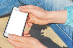 En kvinna som rymmer en vit mobiltelefon med en tom sk?rm royaltyfri bild En kvinna som rymmer en vit mobiltelefon med en tom sk?rm royaltyfri bild