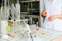 En kvinnlig laborant, en doktor, en kemist, arbeten med flaskor, provrör, gör lösningar, mediciner, blandningingredienser royaltyfri bild En kvinnlig laborant, en doktor, en kemist, arbeten med flaskor, provrör, gör lösningar, mediciner, blandningingredienser royaltyfri bild