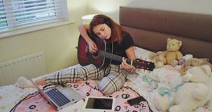 En la muchacha del adolescente del fin de semana pase el tiempo en su sitio que juega en una guitarra su tableta y el cuaderno es metrajes En la muchacha del adolescente del fin de semana pase el tiempo en su sitio que juega en una guitarra su tableta y el cuaderno es metrajes