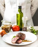 En las especias de la tabla, las verduras y un plato del medallón frito Foto de archivo libre de regalías