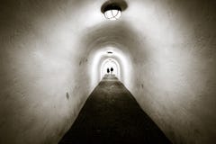 En lång tunnel med vita väggar och det välvda taket Två personer ar royaltyfria bilder En lång tunnel med vita väggar och det välvda taket Två personer ar royaltyfria bilder