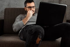 En man h?ller ?gonen p? en vuxen video p? en b?rbar dator, medan sitta p? soffan Begreppet av pornografi, m?ns behov, pervers man royaltyfri fotografi En man h?ller ?gonen p? en vuxen video p? en b?rbar dator, medan sitta p? soffan Begreppet av pornografi, m?ns behov, pervers man royaltyfri fotografi
