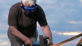 En man i ålder klipper av en metallvinkelmolar på solnedgången Härlig himmel bak arbetaren arkivfilmer En man i ålder klipper av en metallvinkelmolar på solnedgången Härlig himmel bak arbetaren arkivfilmer
