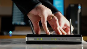 En man kopplar från Ethernetkablarna från WAN porten och LAN-portar av den WiFi routeren En man kopplar från Ethernetkablarna från WAN porten och LAN-portar av den WiFi routeren