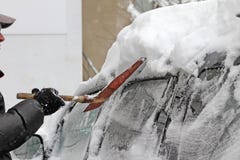 En man med en metallskyffel gör ren bilen från snö på gatan efter stor snöstorm i staden, alla bilar under snö, iskalla vägar, sn royaltyfri foto En man med en metallskyffel gör ren bilen från snö på gatan efter stor snöstorm i staden, alla bilar under snö, iskalla vägar, sn royaltyfri foto