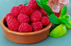 En maträtt av nya mogna saftiga hallon, med mintkaramellen och limefrukt royaltyfri bild En maträtt av nya mogna saftiga hallon, med mintkaramellen och limefrukt royaltyfri bild